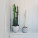 Iris Hantverk wooden handled toilet brush inside concrete holder with plant in bathroom