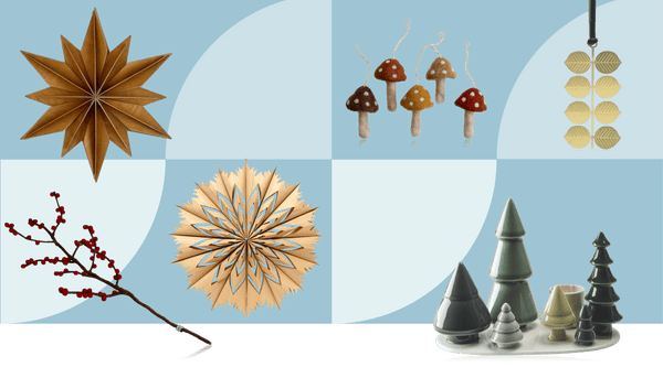 Natural Scandinavian Christmas decorations inspired by the outdoors including birch wood star ornaments, felt mushrooms, brass leaf garland and ceramic tree candleholders in earthy tones on pale blue background