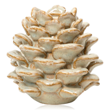 A ceramic sculptural candle holder shaped like a pine cone featuring a glossy off-white glaze with subtle brown speckling and warm tan edges, set against a plain white background.