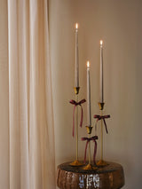 a hallway scene with a set of three lit silver candles in Broste Copenhagen's Ria brass-finish candle holders 