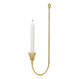 A brass-finished metal wall sconce from Broste Copenhagen holding a single white taper candle, shown against a plain white background.