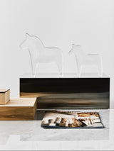 pair of Kosta Boda clear glass horses in two sizes standing on a plinth