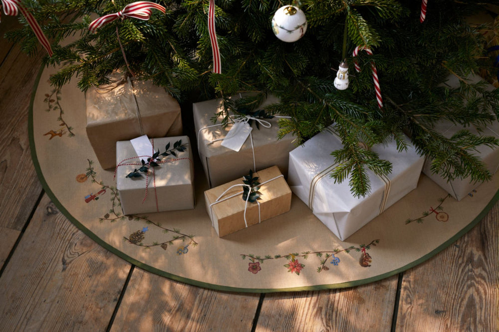 Gifts wrapped in brown and white paper under a nordic Christmas tree on a decorative Scandinavian style mat.
